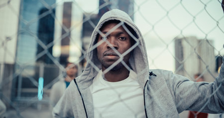 Portrait of a Handsome African American Man Holding the Fence, Posing and Looking at Camera while Standing Outdoors in an Urban City Location. Stylish Diverse Friendsの写真素材