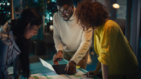 Group of Young Successful Businesspeople Making a Team Meeting in Conference Room in Creative Agency. Excited Diverse Team Using Laptop Computer, Discussing a New Corporateの写真素材