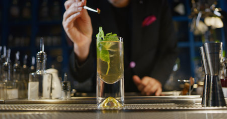 Barman making a cocktail at the bar counter, close-up