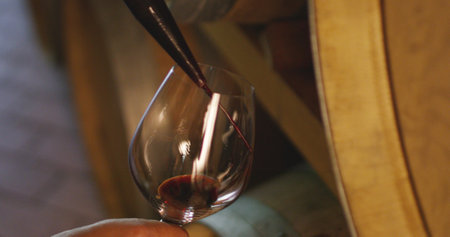 Detail of pouring red wine into a glass from a wooden barrelの写真素材