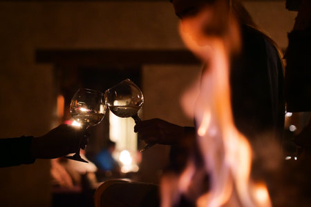 Close-up of two people toasting wineglasses in front of the fireplaceの写真素材