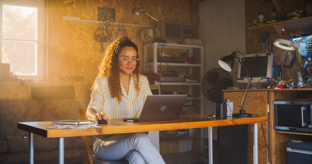 Hispanic Female Programmer Writing Code On Laptop Computer In Garage At Home. Woman Working On...