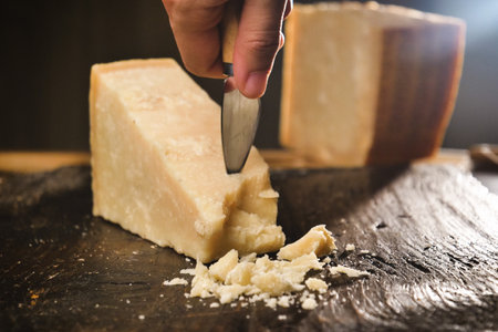 Parmesan cheese on a wooden board with a knife and a knifeの写真素材