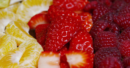 Closeup of fresh strawberries and raspberries with slices of orangesの写真素材
