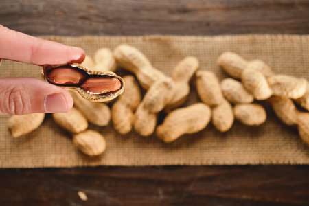 Peanuts in shell on sackcloth and wooden background, top viewの写真素材