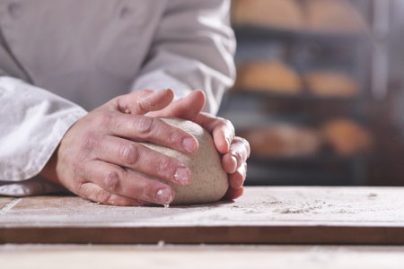 Male hands kneading dough on a wooden table in the kitchen