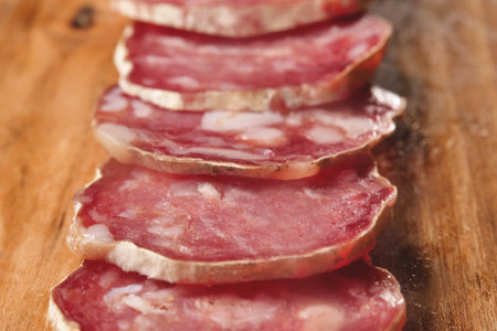 Slices of salami on a wooden board, close-upの写真素材