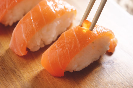 sushi with chopsticks on wooden cutting board, shallow dofの写真素材