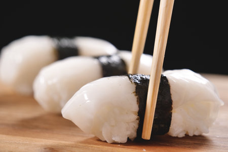 Japanese sushi with chopsticks on a wooden board. Black background.の写真素材