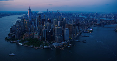 Evening Panorama Around the Wall Street Financial District in New York City, USA. Dark Aerial Shot with Lit Office Buildings and Skyscrapers on a Summer Night with Deep Blue Skyの写真素材