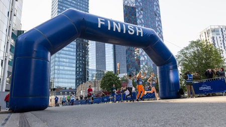 Smiling Group of People Participating in a City Marathon. Wide Shot of Diverse Race Runners Reaching...