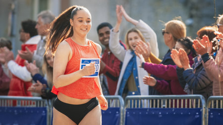 Portrait of a Woman Running and Participating in a Marathon in a Park. Strong Athletic Female Jogger Racing Other Runners with Determination for the First Place in the Finish Lineの写真素材