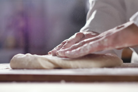 Female hands kneading dough on a table in the kitchen.の写真素材
