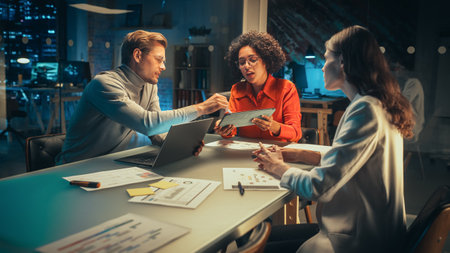Diverse Team of Young Managers Discussing Work at a Meeting in Office at Night. Successful Business...