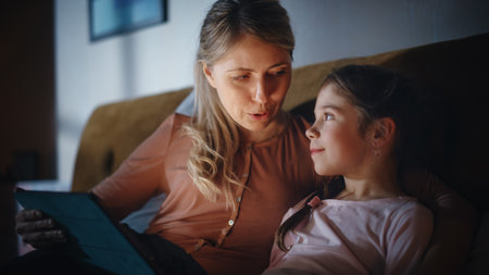 Close Up Portrait of a Mother Reading a Fairytale from a Tablet Computer to Her Lovely Daughter in...