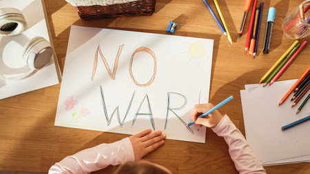 Top View: Little Girl Drawing NO WAR! in Protest against Evil, Greedy People who Bring Only Poverty, Violence and Destruction to Our Beautiful Planet. Young Sad Child Trying to Bring Peace By Her Ownの写真素材