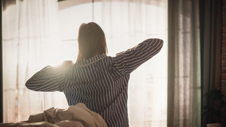Beautiful Young Woman Waking up in the Morning, Stretches and Gets Out of Bed, Sun Shines From the...
