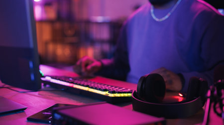 Gamer Putting on Headphones and Playing Online Video Game on Computer. African American Male...