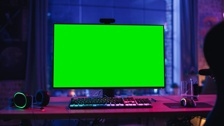 Gaming at Home: Empty Gamer Station with Player's Personal Computer with Green Screen Chroma Key Display Standing on a Wooden Desk in Cozy Loft Apartment with Neon Lights.の写真素材