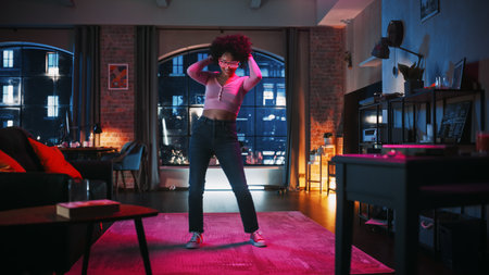 Portrait of Diverse Multiethnic Young Black Female Dancing in Futuristic Neon Glowing Glasses, Having a Party at Home in Loft Apartment. Recording Funny Viral Videos for Social Media.の写真素材