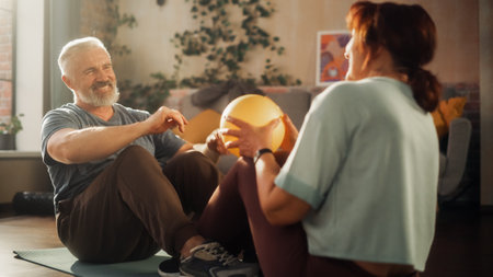 Middle Aged Couple Doing Core Strengthening Exercises and Crunches Workout Together at Home in Sunny Living Room. Senior Man and Woman Motivate Each Other to be Healty.の写真素材