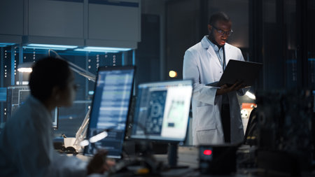 Modern Electronics Research, Development Facility: Professional Black Engineer Holding Laptop Computer Standing in the High-Tech Laboratory. Scientists Design Silicon Microchips, Semiconductorsの写真素材