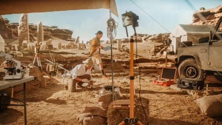 Archaeological Digging Site: Great Female Archeologist Work on Excavation Site, Carefully Cleaning with Brushes and Tools Newly Discovered Ancient Civilization Cultural Artifacts, Fossil Remainsの写真素材