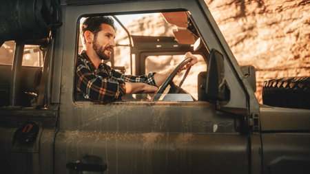 Desert Road Trip: Portrait of Handsome Male Explorer Looking out of Car Driver Window and Smiling. Adventurer Traveling through the Canyon on His Offroad SUV. Vacation Journey Through Marvelous Natureの写真素材