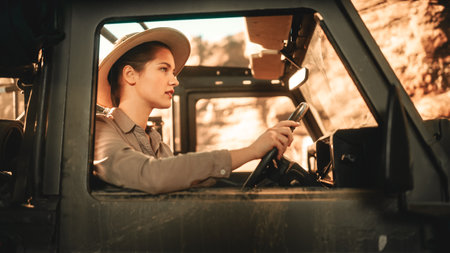 Desert Road Trip: Portrait of Beautiful Female Explorer Looking out of Car Driver Window and Smiling. Woman Adventurer Traveling through the Canyon on Her Offroad SUV. Journey Through Marvelous Natureの写真素材