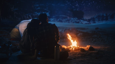 Happy Couple Camping in the Canyon, Sitting Watching Campfire and Starry sky Together, She Rests Her Head on His Shoulder. Two Traveling people On Inspirational Vacation Trip Marvel at Milky Way Starsの写真素材