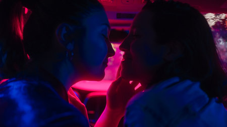 Romantic Young Adult Lesbian Female Couple Kiss on the Front Seat of Their Car on a Rainy Night in...