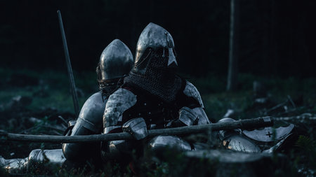 Two Medieval Knights Sitting on Battlefield amidst Dead Enemies. Last Surviving Crusaders, Soldiers, Warriors after Battle. Destruction of War, Invasion, Crusade. Cinematic Historic Reenactmentの写真素材