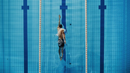 Aerial Top View Male Swimmer Swimming in Swimming Pool. Professional Athlete Training for the Championship, using Front Crawl, Freestyle Technique. Top Down View.の写真素材