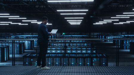 Data Center Engineer Using Laptop Computer. Server Farm Cloud Computing Specialist Facility with African American Male System Administrator Working with Data Protection Network for Cyber Security.の写真素材