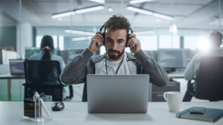 Office: Portrait of Smiling IT Programmer Put on Headphones, Work on Desktop Computer. Male Website...