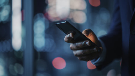 Night Office: Successful Black Businessman Wearing Suit Standing, Using Smartphone. CEO Browsing...