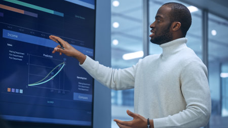 Diverse Modern Office: Successful Black Digital Entrepreneur Uses Tablet Computer and TV Screen with...