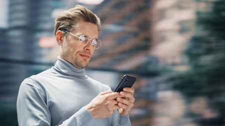 3Street Shot: Handsome Caucasian Man Using Smartphone in the Big City. Creative Professional Using...