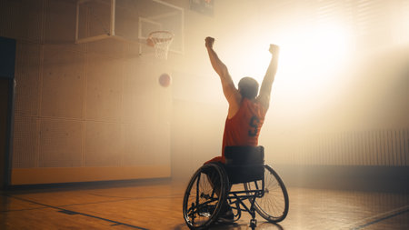Wheelchair Basketball Play: Player Celebrating Perfect Goal with Raised Hands after Successful Shoot. Skill of a Winning Person with Disability. Shot with Warm Colorsの写真素材