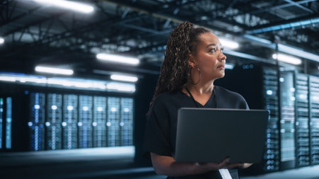 Mixed RaceFemale IT Specialist Uses Laptop Computer in Data Center. Server Farm Cloud Computing...