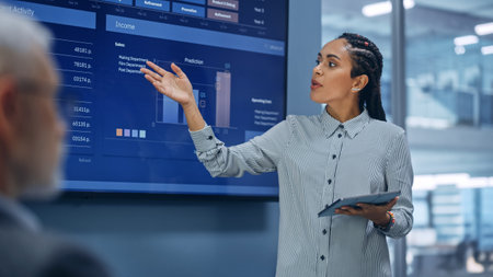Diverse Modern Office: Successful Black Digital Entrepreneur Uses Tablet Computer and TV Screen with...