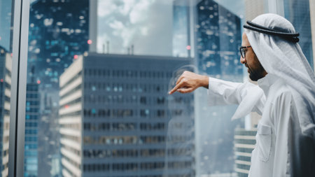Successful Muslim Businessman in Traditional White Kandura Riding Glass Elevator to Office in Modern Business Center. Arab Male Interacting With Mock Up Holographic Screen in the Lift Concept.の写真素材
