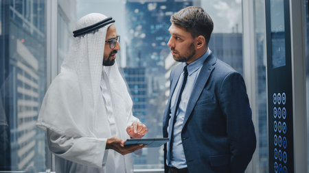 European Businessman Talking with Arab Investment Partner while Riding Glass Elevator to Office in a Modern Business Center. International Corporateの写真素材
