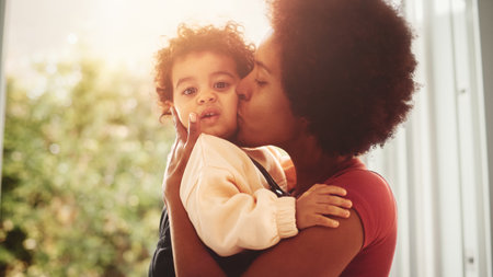 Loving Mother Hugging and Holding Adorable Baby Boy at Modern Home Living Room. Happy Mom Kissing...