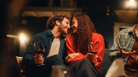 Loving Mixed Race Couple Sitting Together at a Garden Party Celebration with Friends on a Warm Summer Evening. Beautiful Man and Woman Kiss, Talkの写真素材