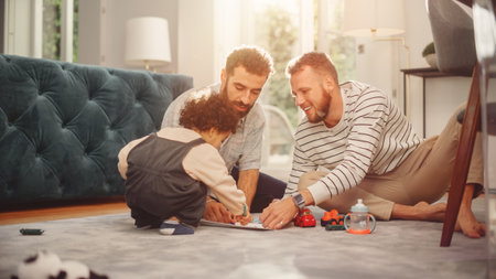 Loving LGBTQ Family Playing with Toys with Adorable Baby Boy at Home on Living Room Floor. Cheerful Gay Couple Nurturing a Child. Concept of Diverseの写真素材