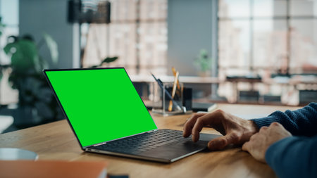 Close Up on Hands of a Caucasian Specialist Working on Laptop Computer with Green Screen Mock Up Display at Home Living Room. Freelance Man Chattingの写真素材