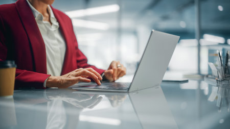 Stylish Bright Office: Anonymous Businesswoman in Stylish Suit Working on Laptop. Female CEO Working Late on Computer to Achieve Best Results. Colorful Shot Focus on Hands and Computerの写真素材
