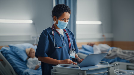 Hospital Ward: Professional Black Latin Female Head Nurse or Doctor Wearing Face Mask Uses Medical Computer. In the Background Patients in Bedsの写真素材