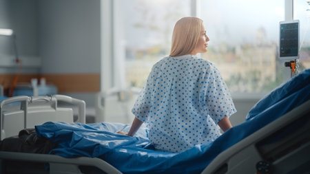 Hospital Ward: Beautiful Caucasian Female Patient Sitting on a Bed, Fully Recovering after Successful Surgery, Covid-19, Sickness she Looks Around andの写真素材